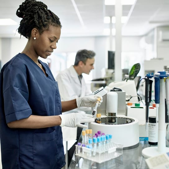 Técnico em patologia vestindo uniforme azul em laboratório de análises
