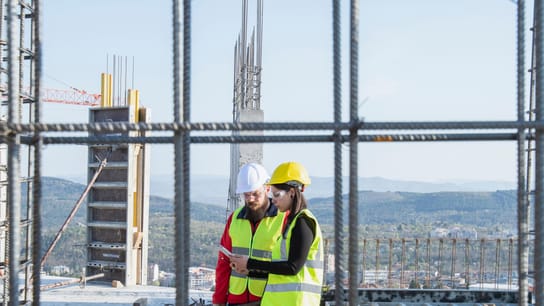 Construction workers standing on outdoor construction site and discuss the building plans.