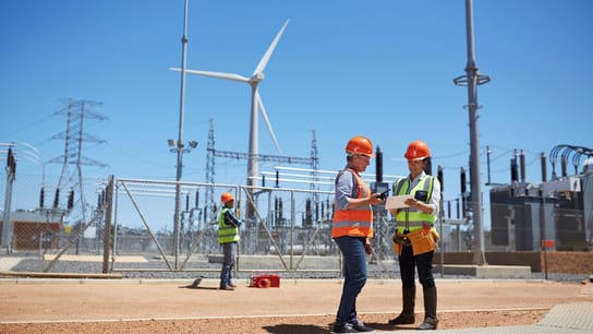 Two construction workers in front of wind turbines