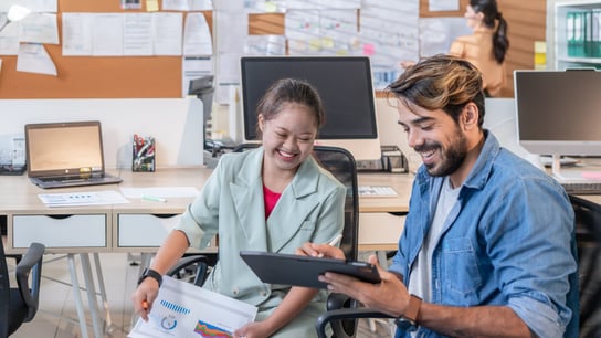 Young businesswoman with Down Syndrome working with her colleague in an office