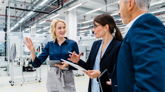 Businesswomen having discussion by businessman at automated factory