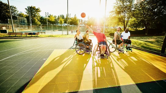 Adaptive athlete taking shot during wheelchair basketball game on outdoor court