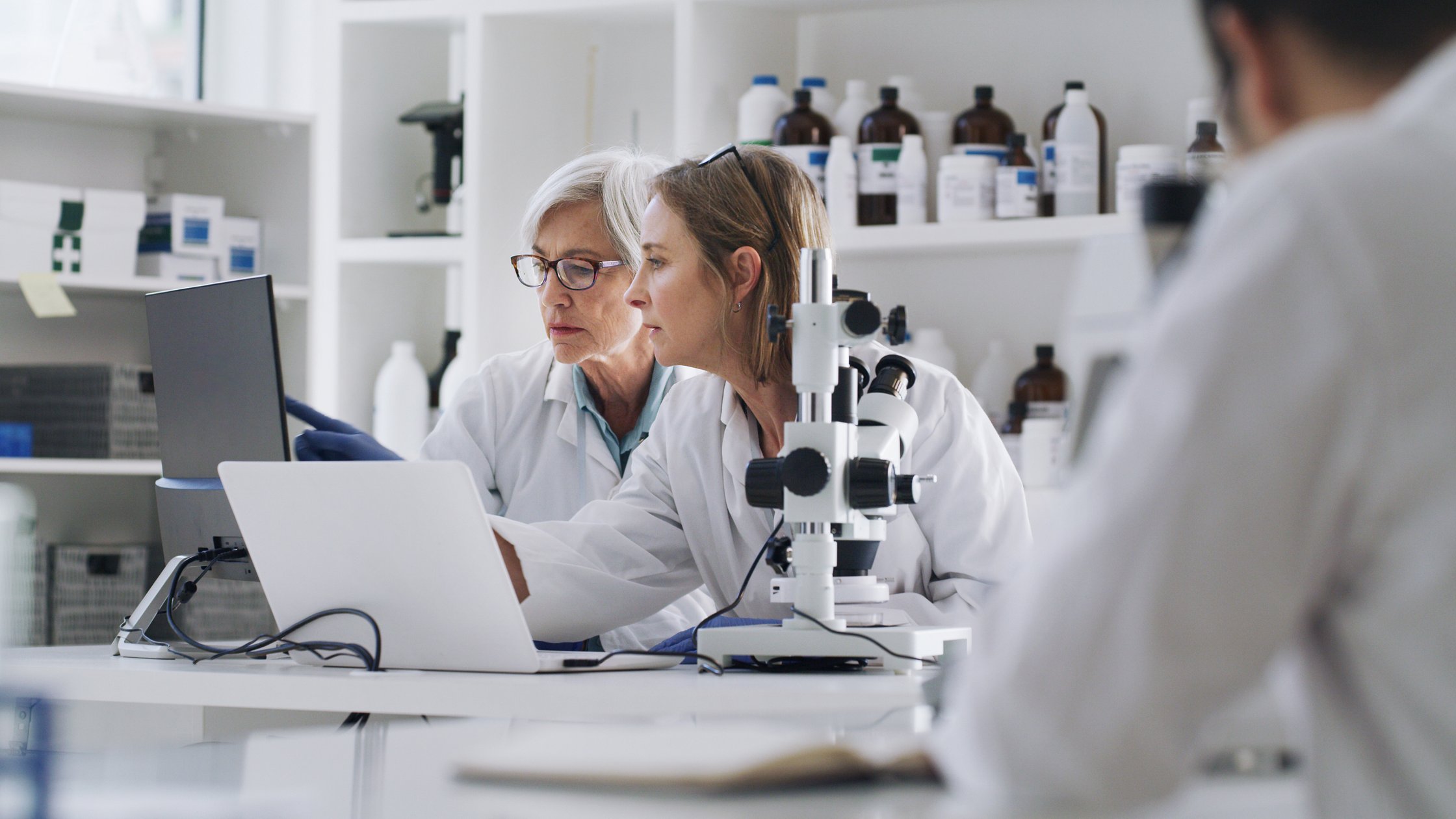 Women scientists in laboratory with laptop and equipment