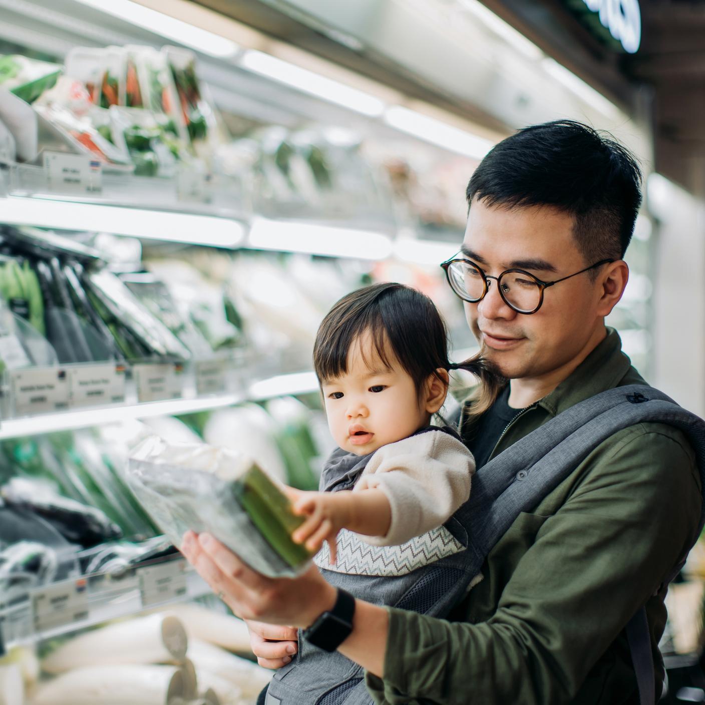 A father holding their child in the grocery isle in a supermarket