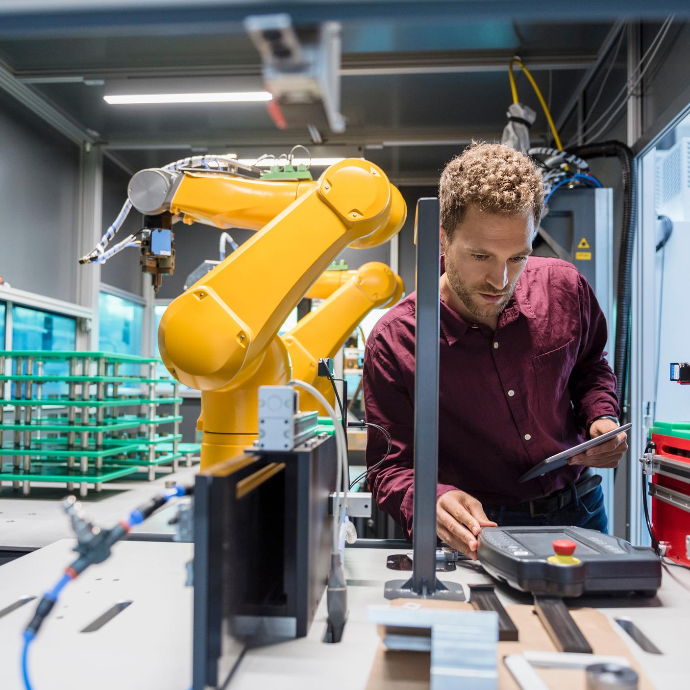 Zakenman controleert industriële robot in hightechbedrijf