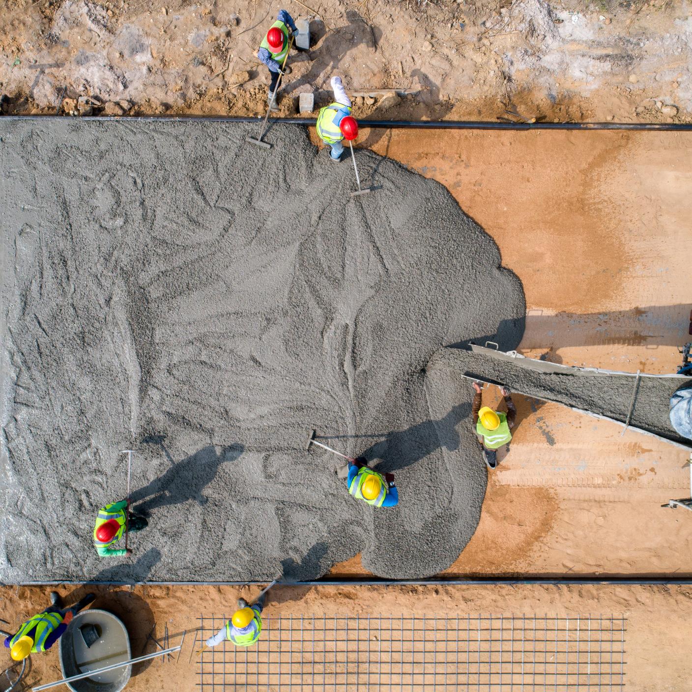 A construction worker pouring a wet concret at road construction site