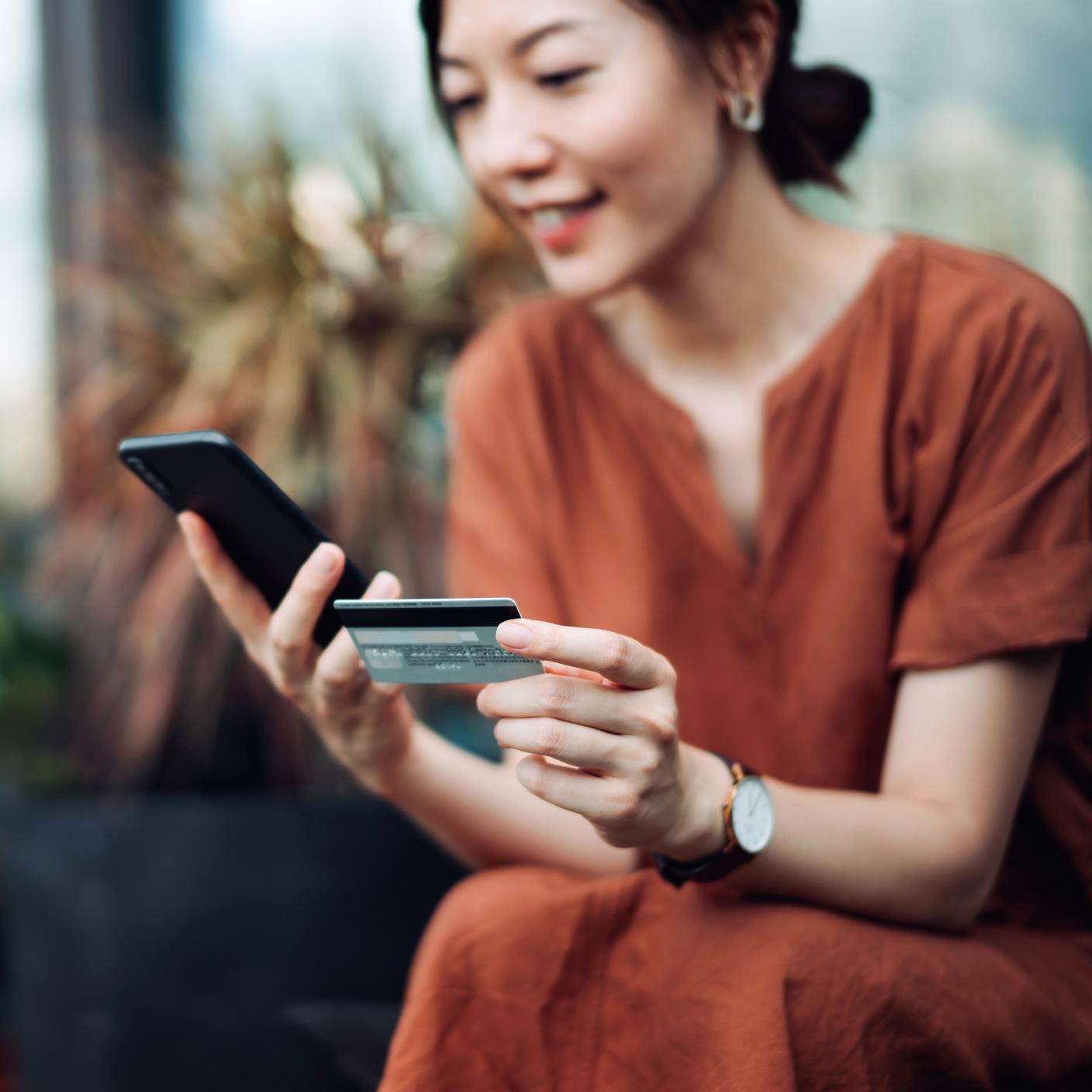 Asian woman shopping online on smartphone and making mobile payment with credit card.