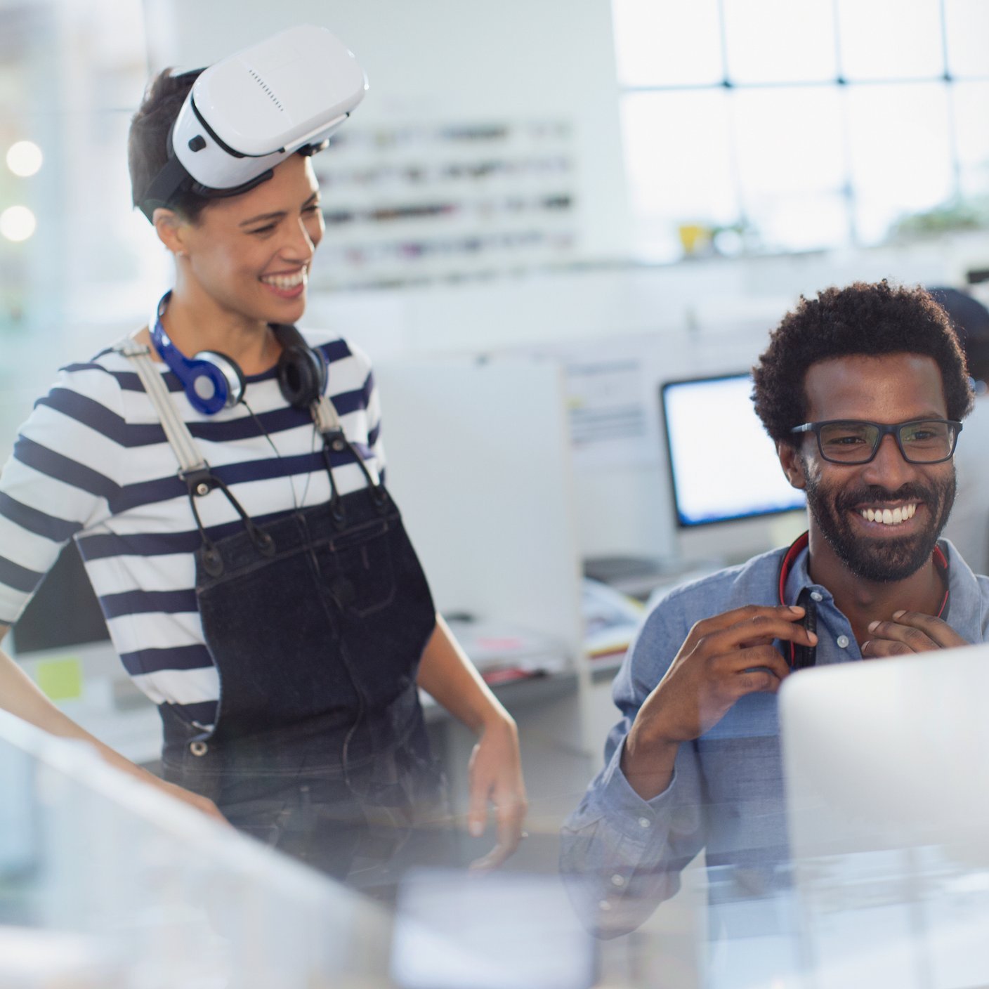 Smiling computer programmers programming virtual reality simulator in office
