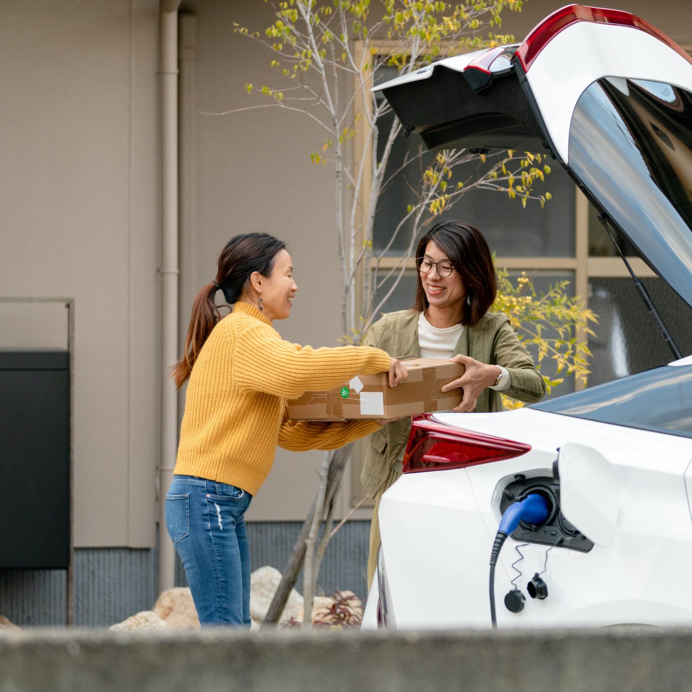 Mid adult women unloading an electric car. Okayama, Japan.