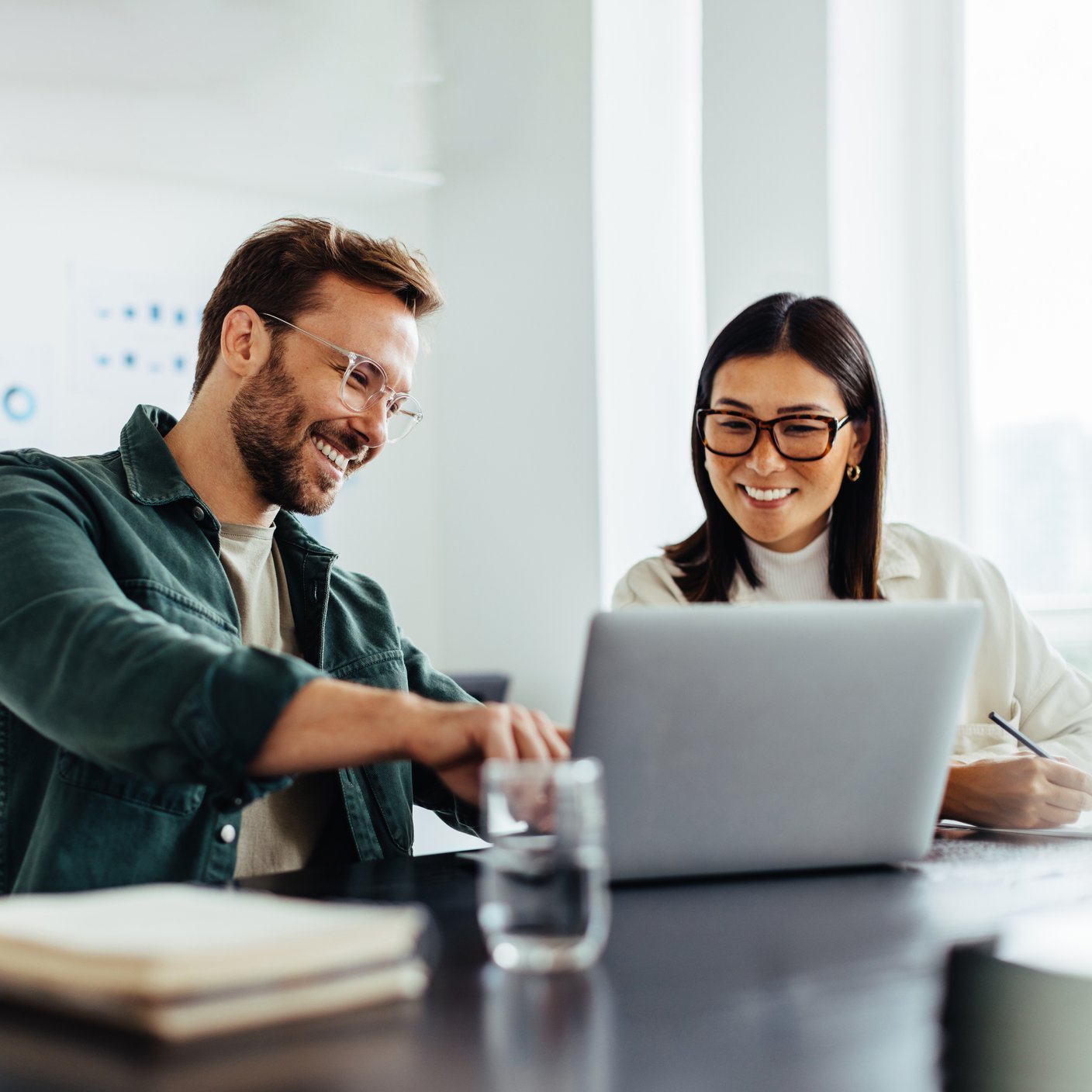 Two business people using a laptop together while sitting in a meeting.