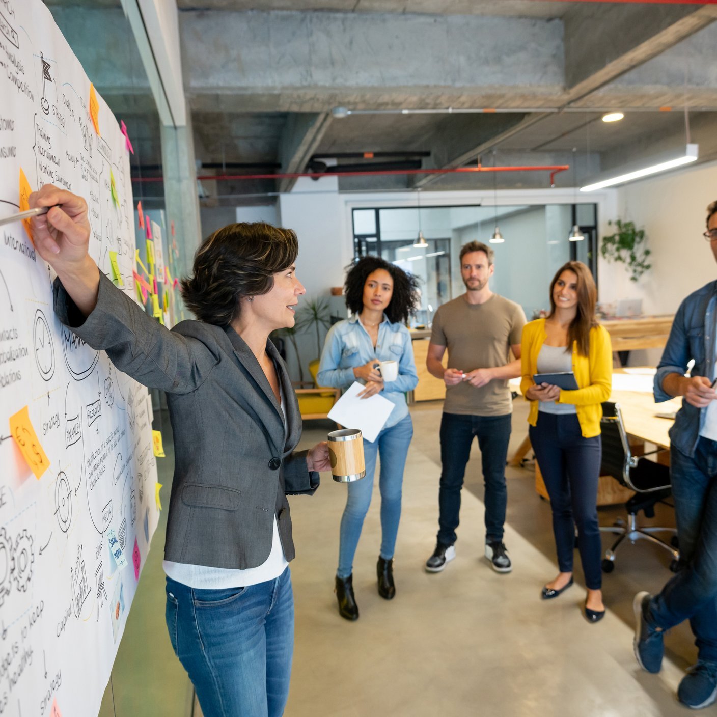 Woman making a business presentation in a meeting at a creative office and pointing to her team her business plan