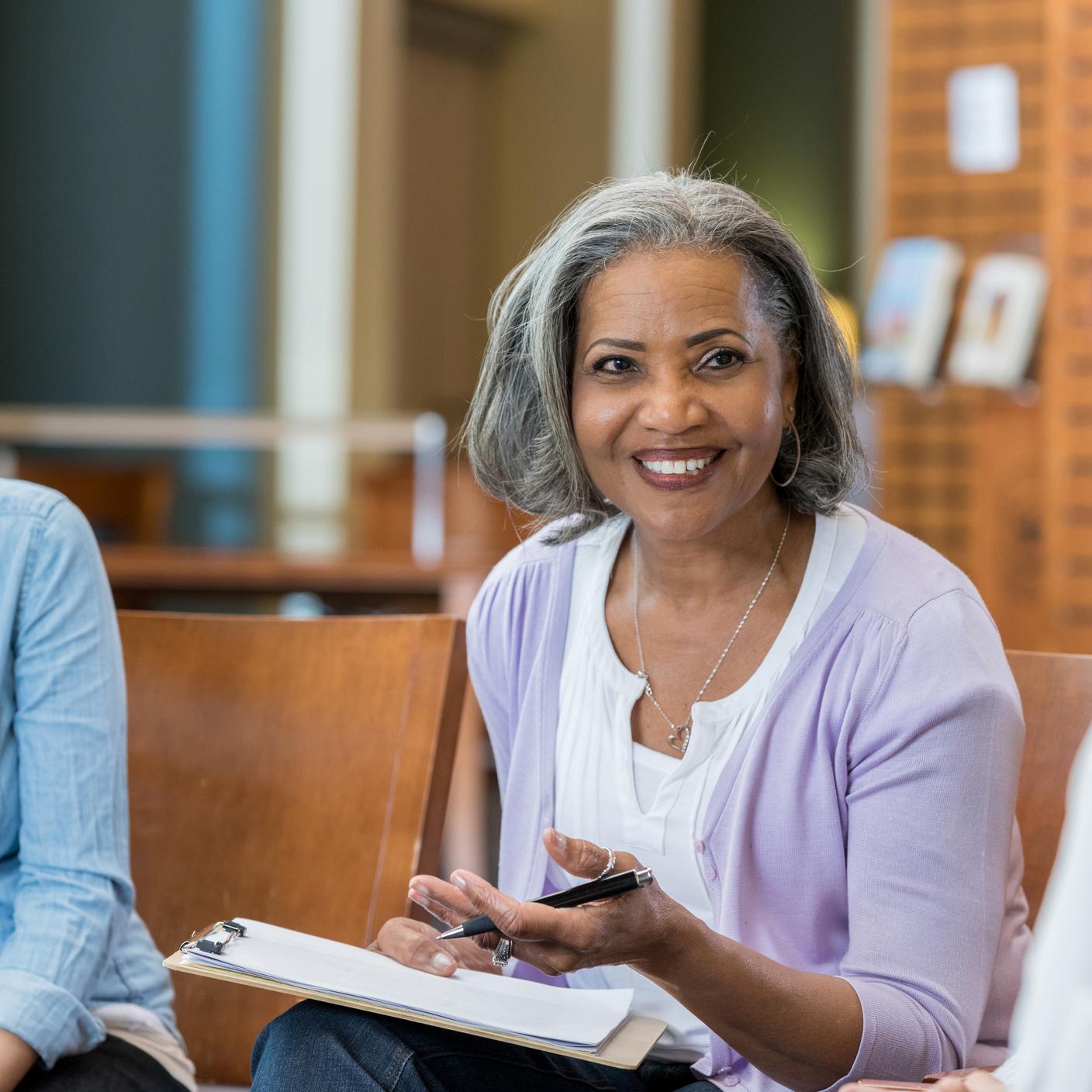 Une femme avec un bloc-notes s’adressant à des personnes