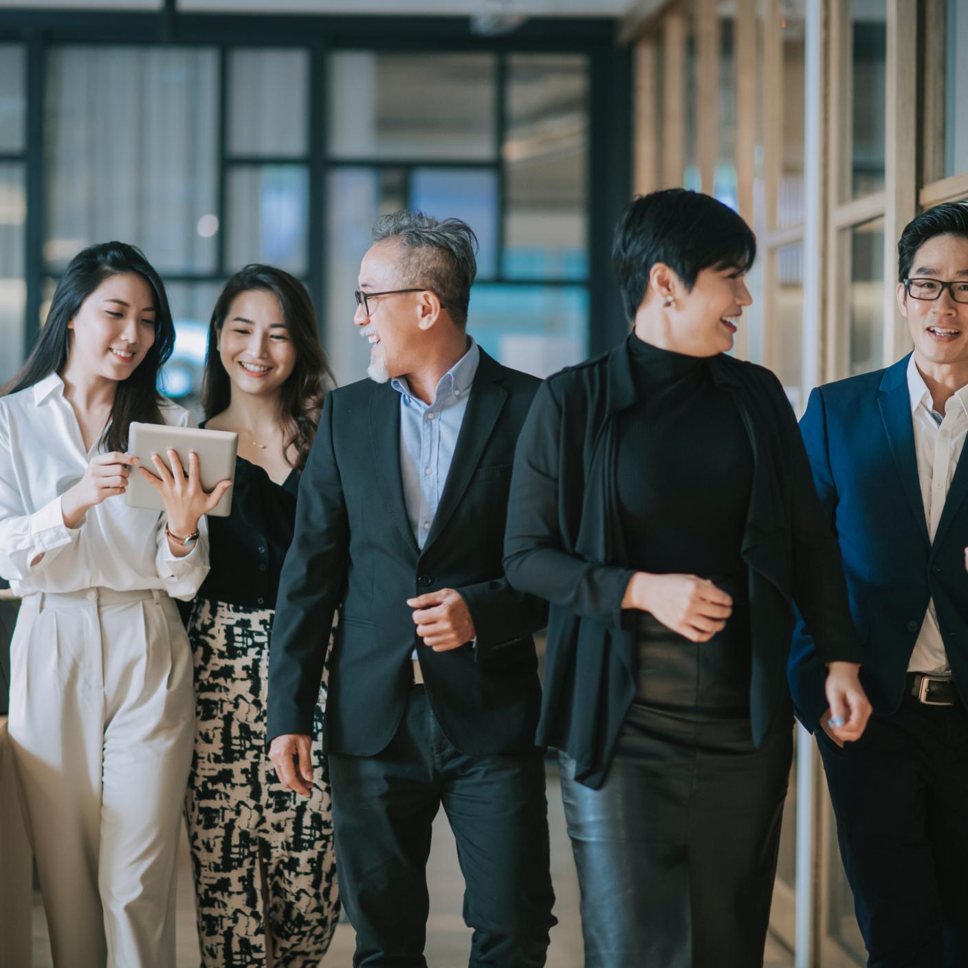 Group of successful office management team having discussion while walking toward camera.