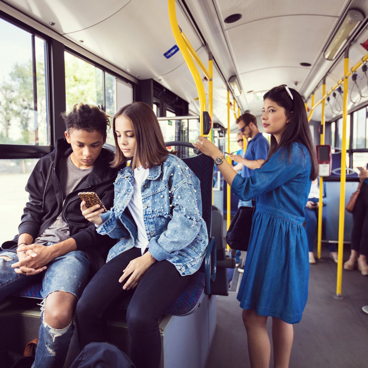 Teenage girl showing mobile phone to boy in bus.