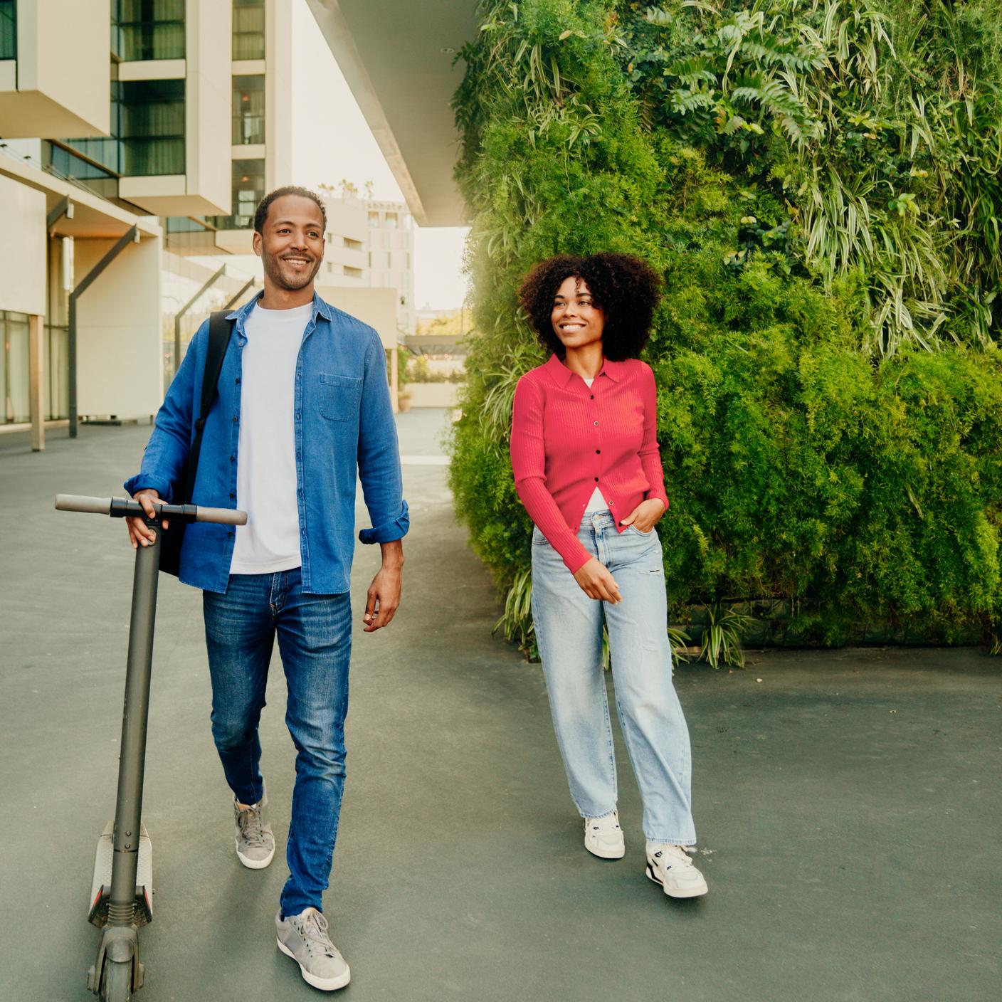 Şehirde yeşil bir alanda yürüyen ve gülümseyen çift