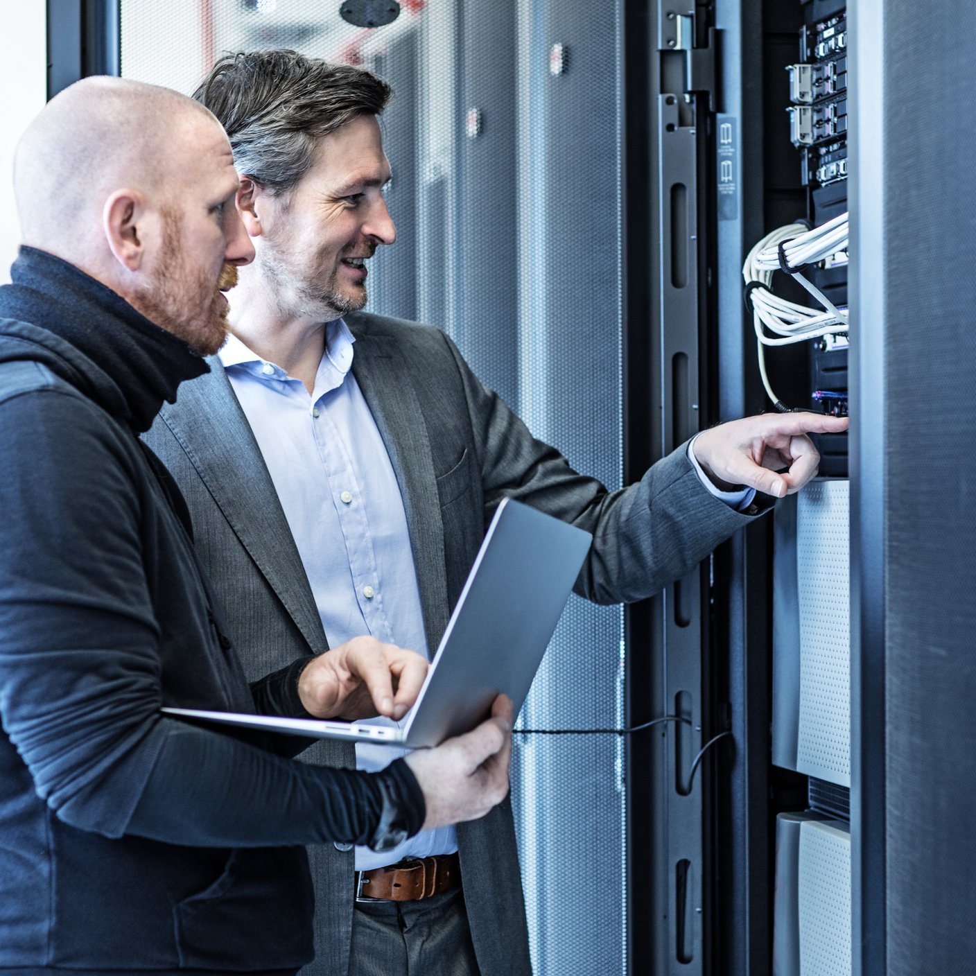 Male Adult Technicians and Manager working together in Server Room Setting.