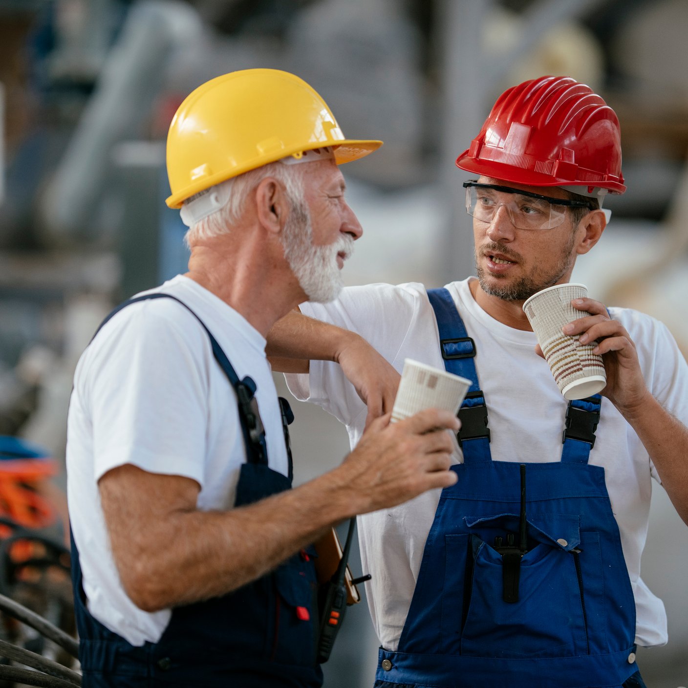 Manual workers having a coffee break in industrial building.