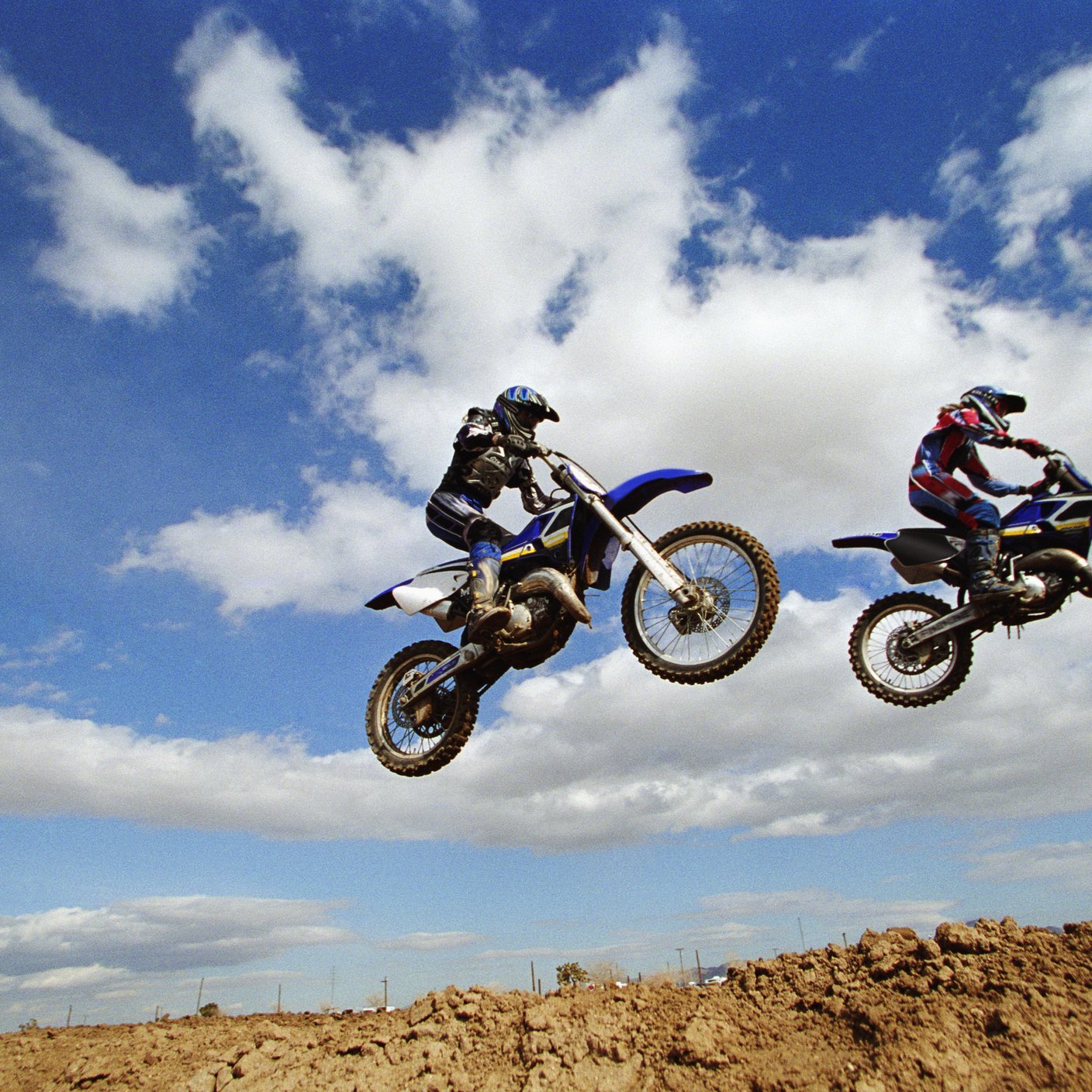 Two motocross bikes in air following jump