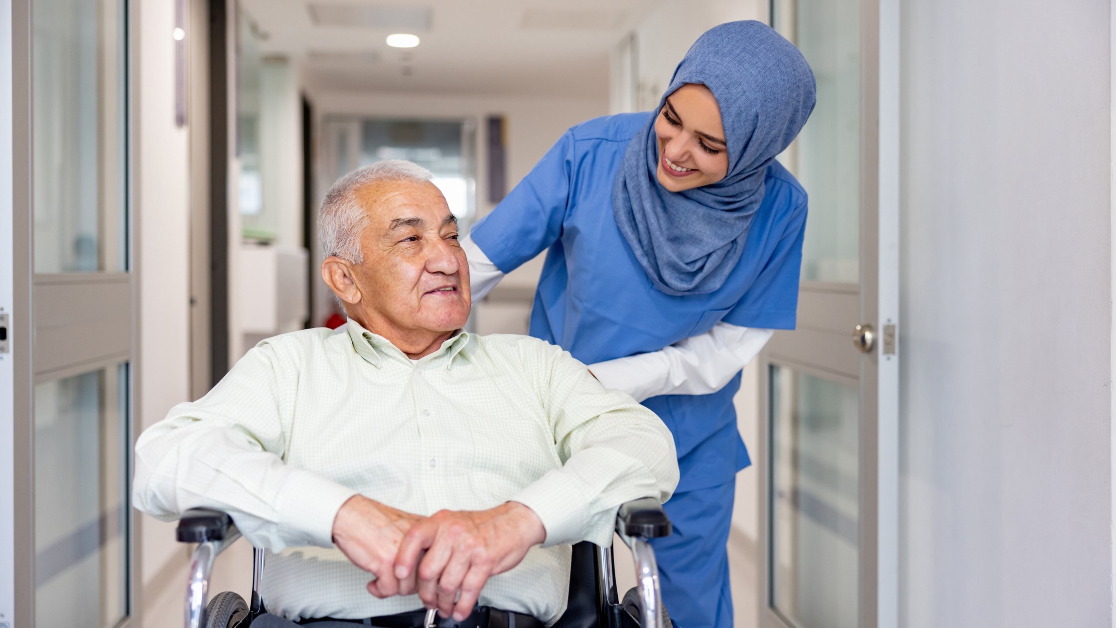Happy nurse taking care of a senior patient leaving the hospital in a wheelchair