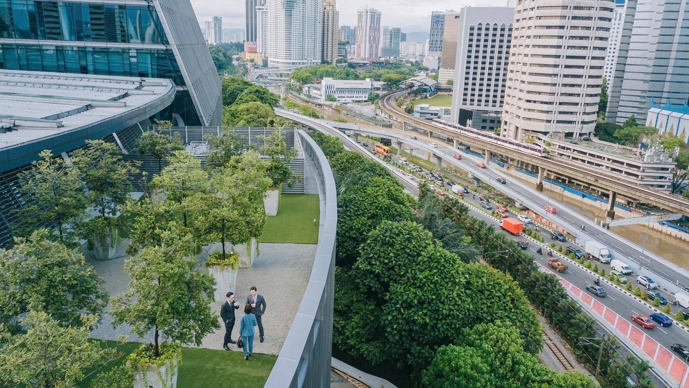 Three business people walking on roof top garden outside a office building.
